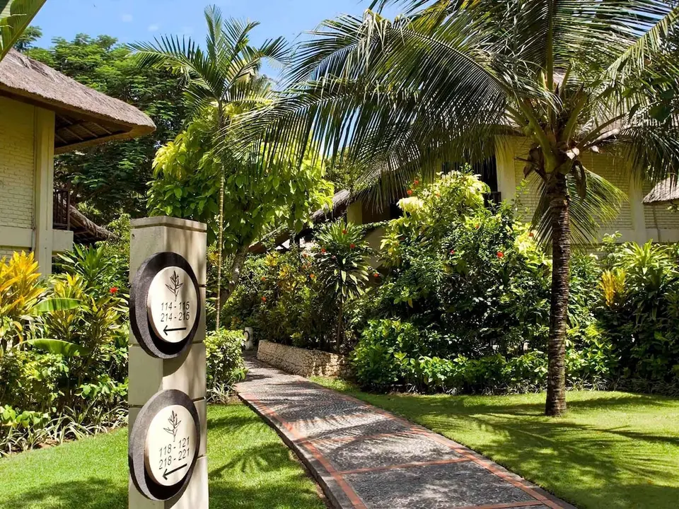 Havegang mellem palmer og værelsesbygninger på Mercure Resort Sanur