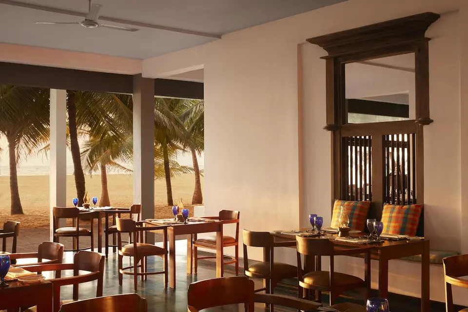 Restaurant på Jetwing Blue med dækkede træborde og åbent kig til stranden og palmerne.