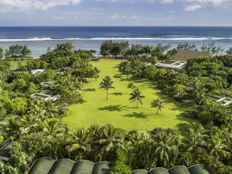 Luftfoto af SO Sofitel Mauritius med grøn plæne, palmer og havet i baggrunden