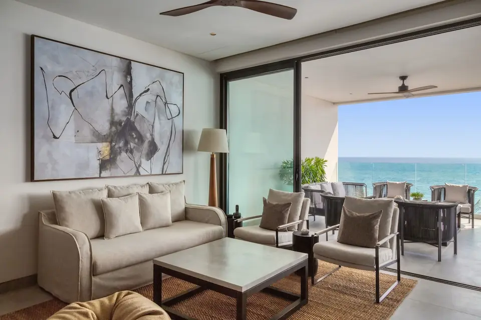 Sofa og to lænestole ved store skydedøre mod en overdækket balkon med havudsigt på Crystal Sands.