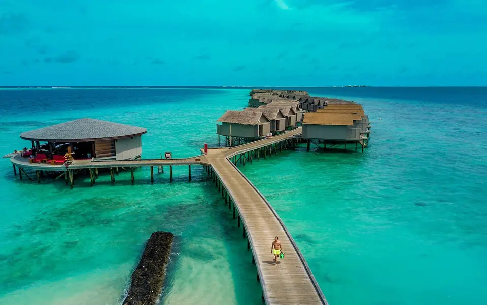 Træbro til bar og vandvillaer over lagunen på Centara Ras Fushi