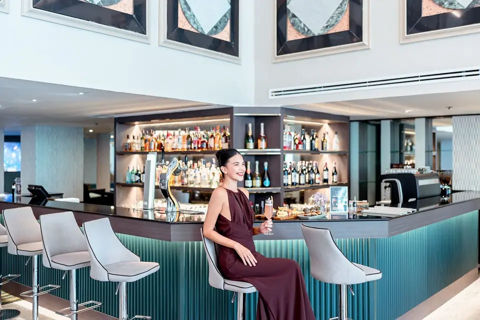 Bar med lyse barstole, grøn front og flasker på hylderne på Rembrandt Hotel Bangkok.