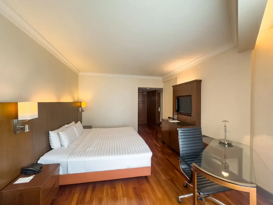 Værelse med dobbeltseng, skrivebord og tv på Rembrandt Hotel Bangkok.