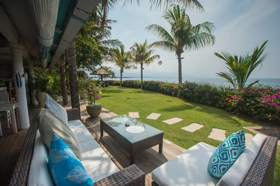 Overdækket terrasse med kurvemøbler og udsigt over haven til havet på Mayo Resort