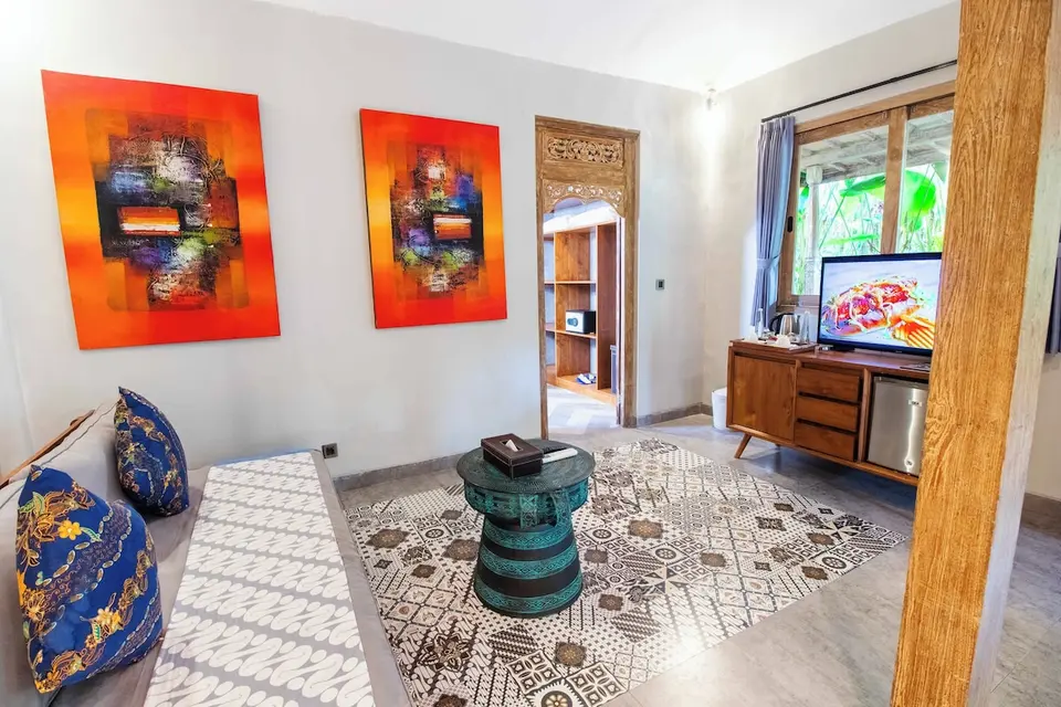 Opholdsplads med sofa, rundt bord og orange vægkunst på Natya Hotel Tanah Lot