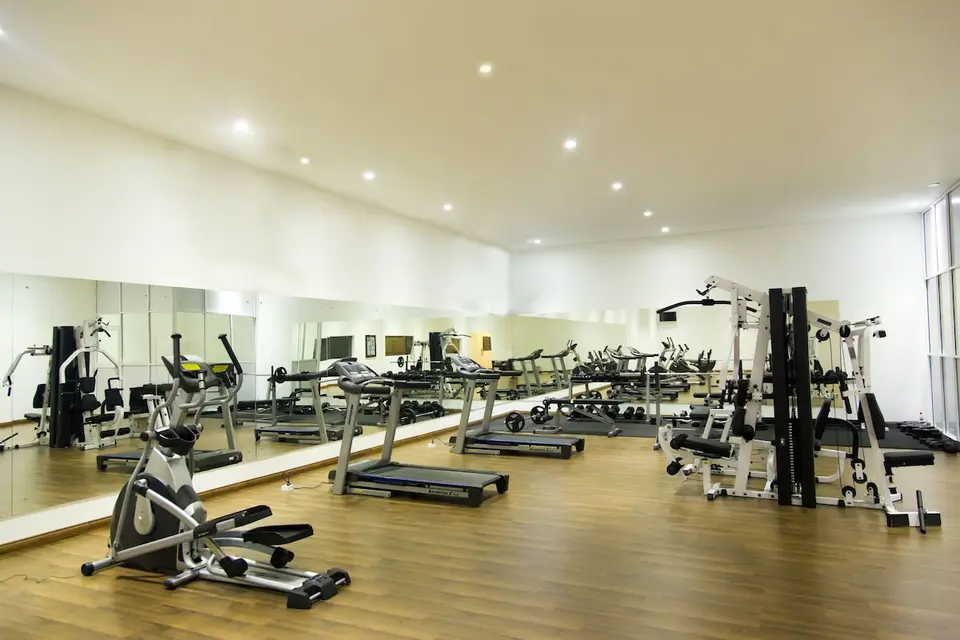 Fitnessrum på Aliya Resort med løbebånd, motionscykel, vægtmaskiner og spejlvæg.