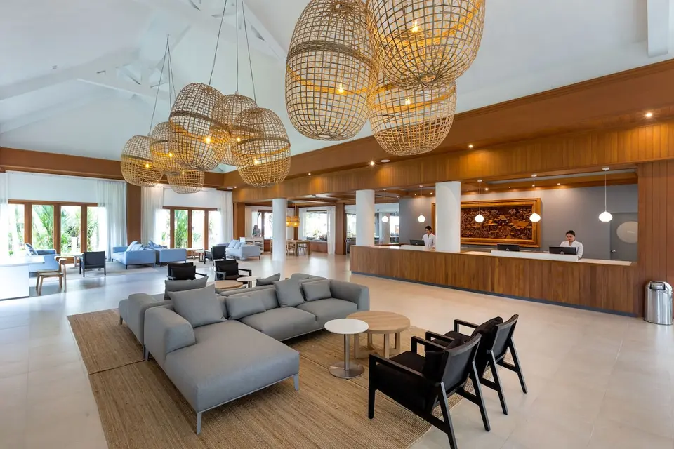 Lys lobby med reception, grå sofaer og store flettede pendler på Sunwing Bangtao Beach.