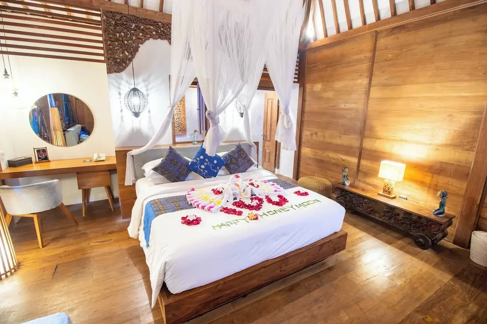 Træværelse med himmelseng dekoreret med blomster på Natya Hotel Tanah Lot