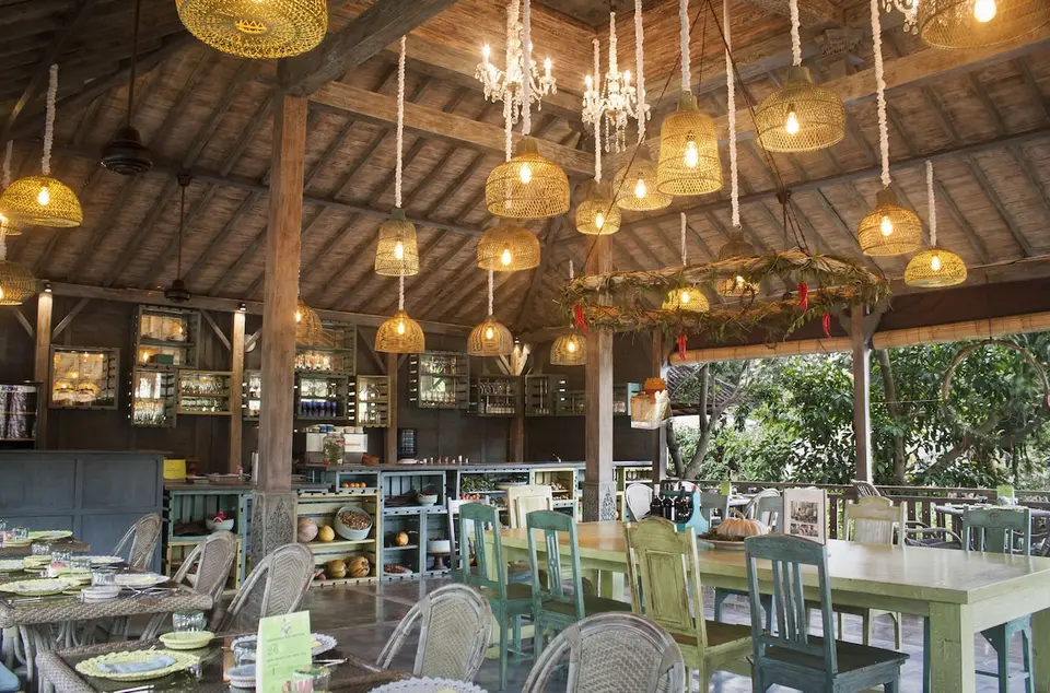 Restaurant med træmøbler og hængende lamper på Adiwana Resort Jembawan