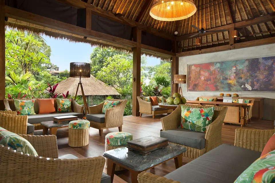 Åben lounge med kurvemøbler og grønne omgivelser på Adiwana Resort Jembawan