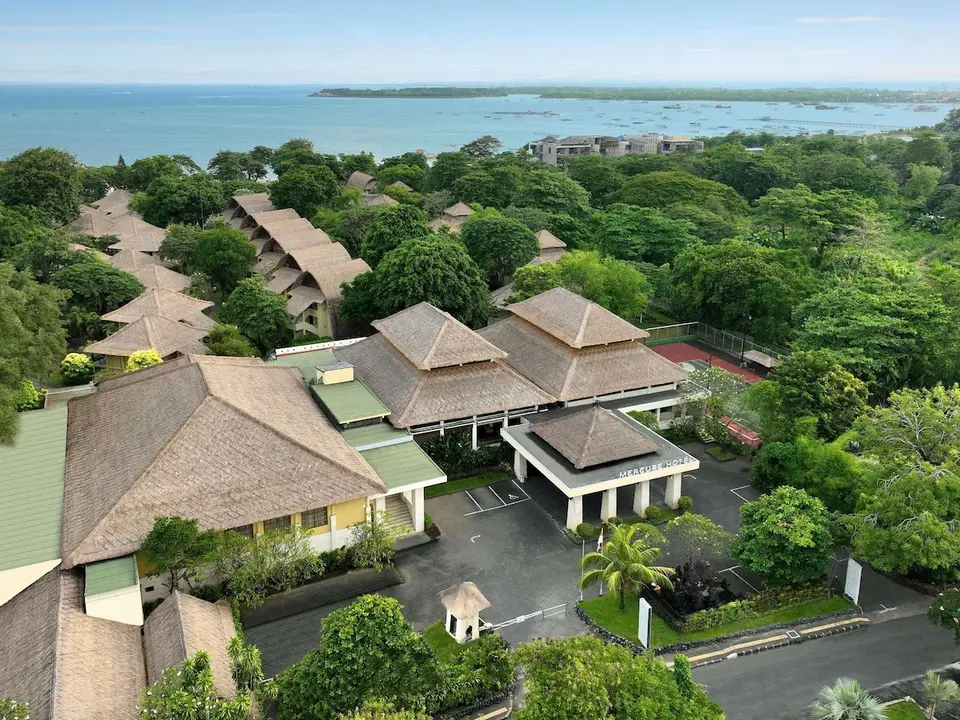 Luftfoto af indkørsel, stråtage og grøn have på Mercure Resort Sanur
