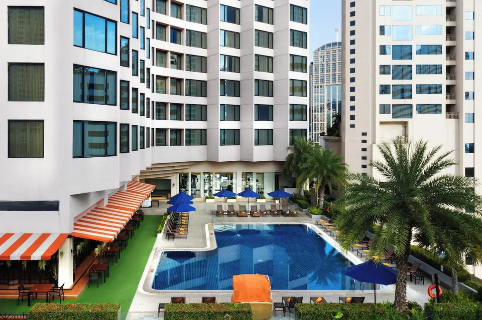 Poolområde set ovenfra med blå parasoller og restaurantterrasse på Rembrandt Hotel Bangkok.
