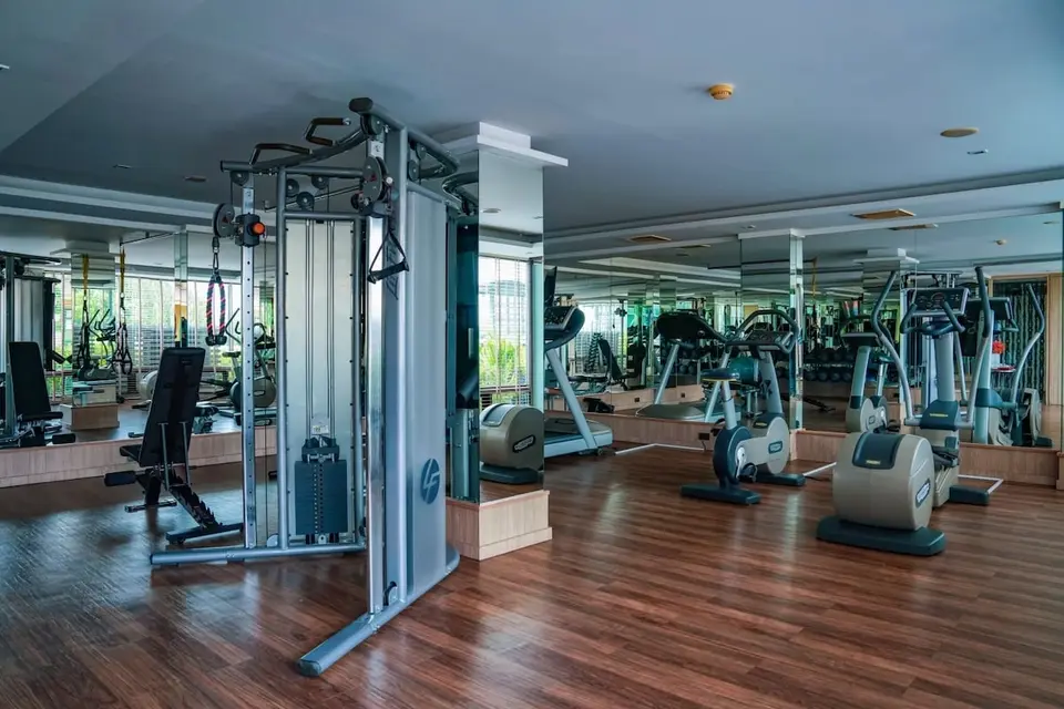 Fitnessrum med træningsmaskiner, motionscykler og spejle.