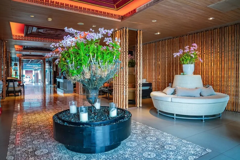 Lobby med orkidéer, rundt siddeområde og mønstret gulv.