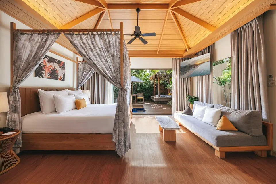 Værelse med himmelseng, sofa og udgang til terrasse på Bandara Samui.