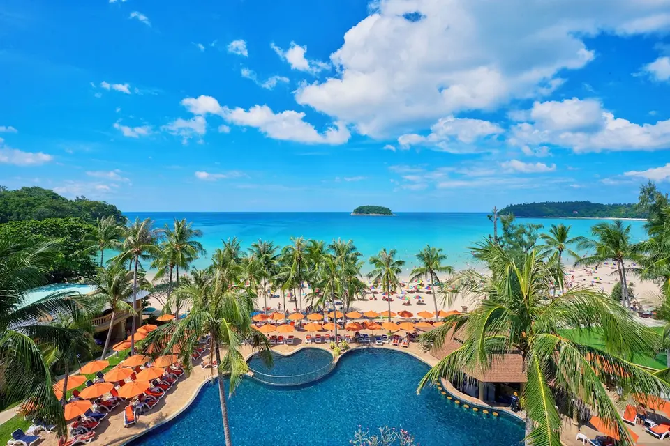 Pool med orange parasoller og palmer foran Kata Beach