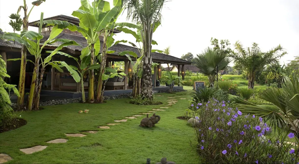 Havegang mellem palmer og blomstrende planter på Blue Karma Dijiwa Ubud.