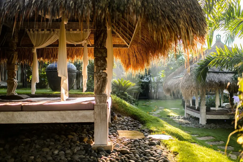 Overdækkede hvilepladser under stråtag i haven på Blue Karma Dijiwa Ubud.