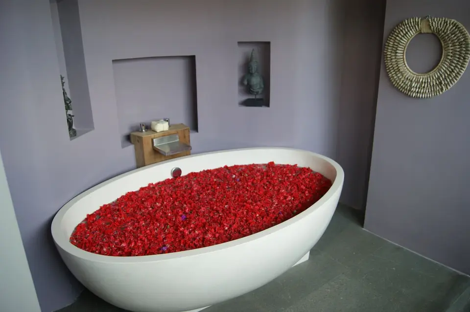 Fritstående badekar fyldt med blomsterblade på Blue Karma Dijiwa Ubud.
