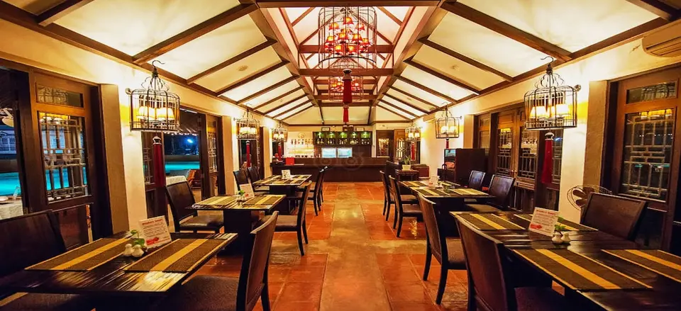 Restaurant med dækkede borde, synlige loftsbjælker og lanterner.