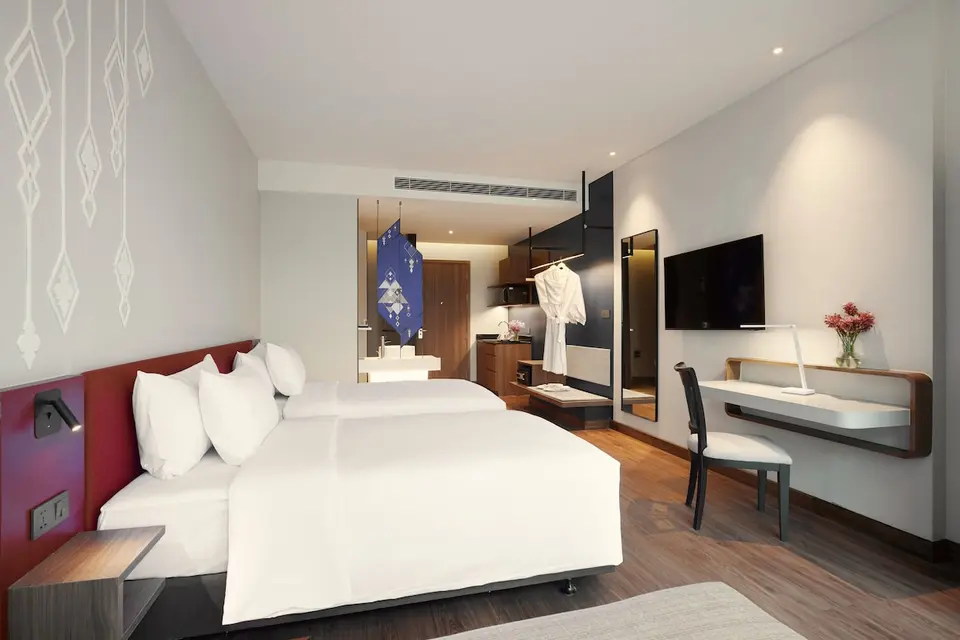 Værelse med to enkeltsenge, skrivebord og åben garderobe på Centara Life Bangkok Phra Nakhon
