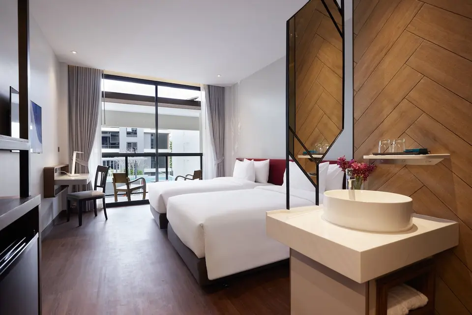 Værelse med to enkeltsenge, håndvask og balkon mod poolgården på Centara Life Bangkok Phra Nakhon
