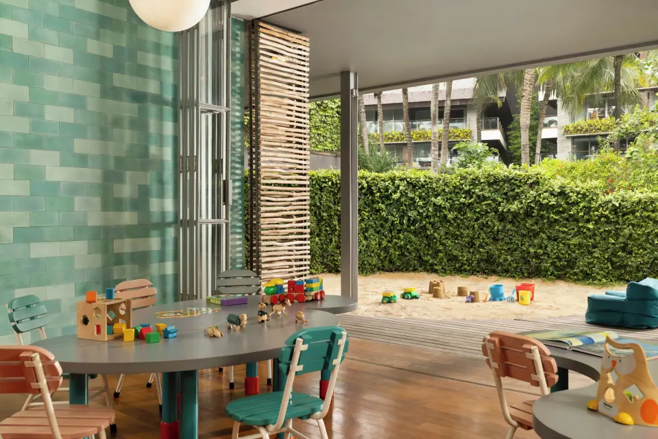 Børneområde på COMO Canggu med små borde, legetøj og adgang til sandlegeplads.