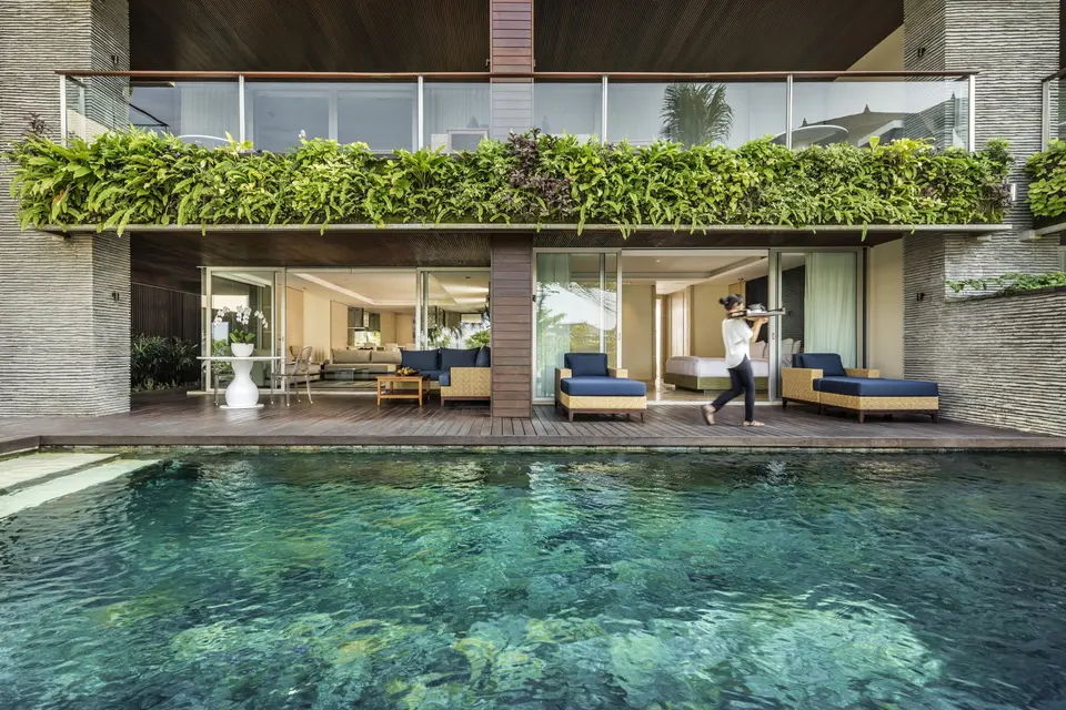 Pool foran en bolig på COMO Canggu med overdækket træterrasse og blå loungemøbler.