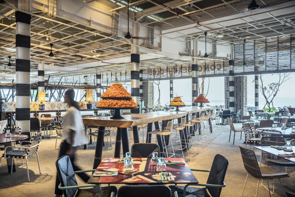 Restaurant på COMO Canggu med dækkede borde, højt loft og åbne sider mod havet.