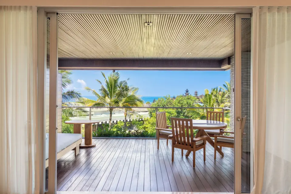 Overdækket terrasse med træmøbler og udsigt mod havet på COMO Canggu