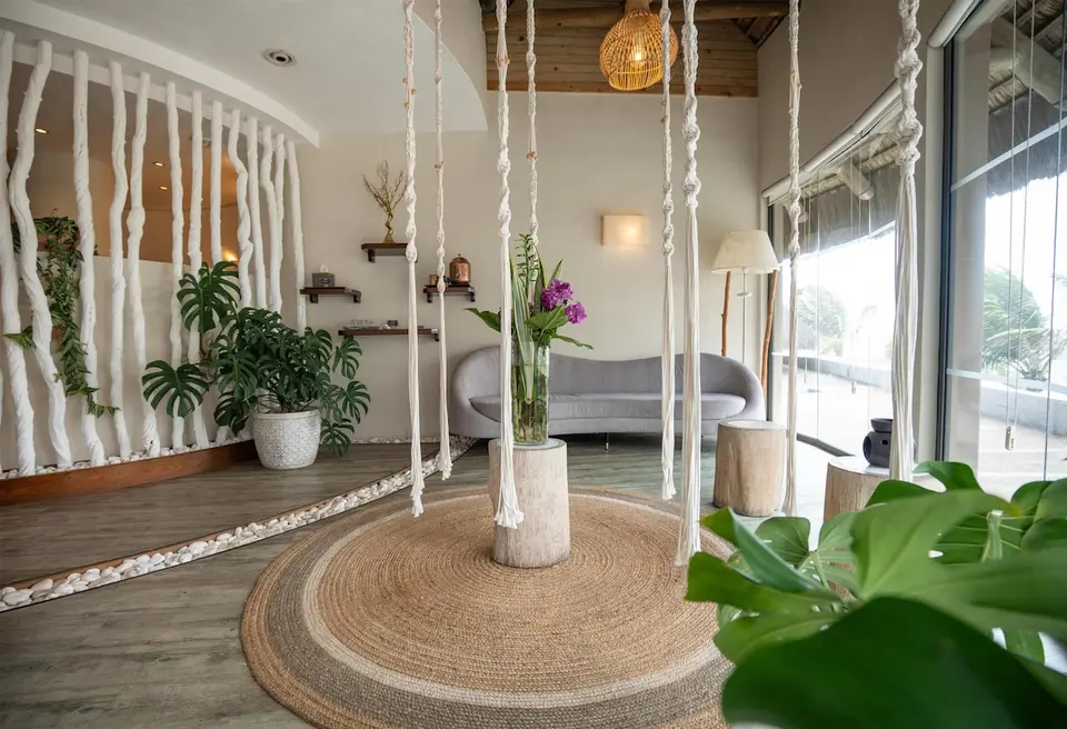 Lyst loungeområde med grå sofa, rundt tæppe og grønne planter