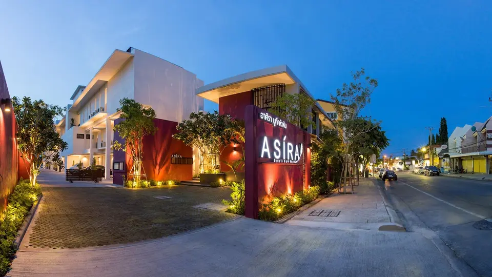 Hotellets indgang og oplyste Asira-skilt ved gaden i skumringen