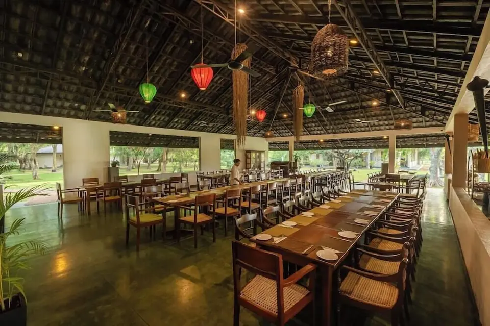 Restaurant på Kassapa Lion Rock med dækkede træborde, højt tag og åbne sider mod haven.
