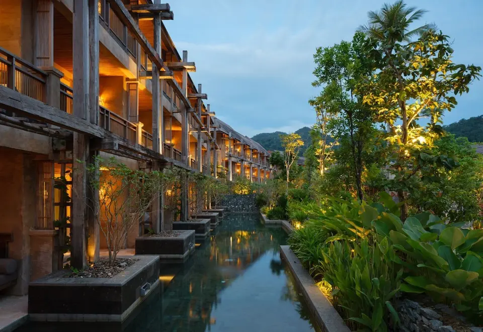 Værelsesbygninger og smalt bassin mellem grønne planter på Dinso Ko Chang