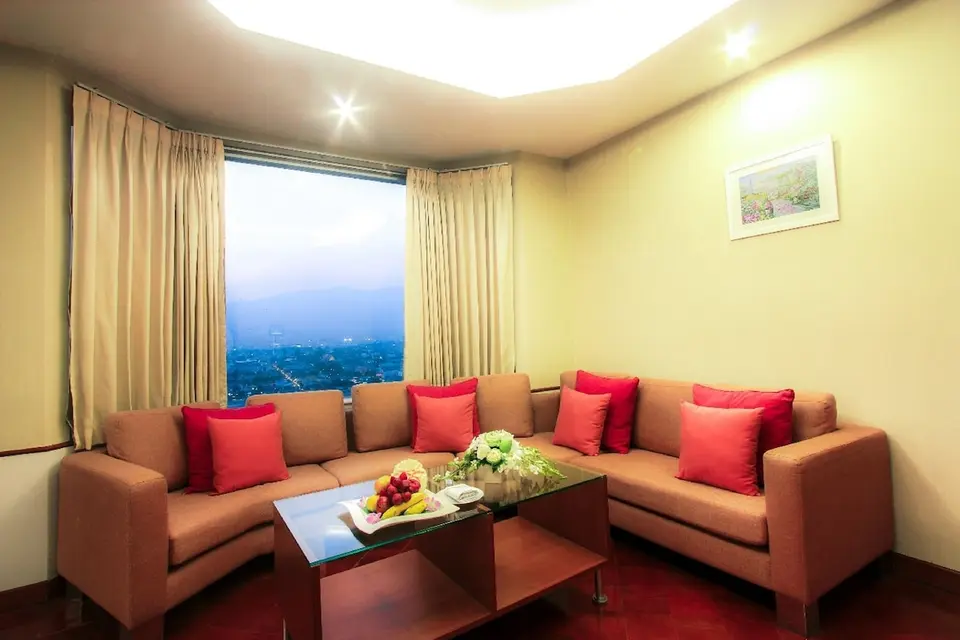 Opholdsstue med hjørnesofa, sofabord og udsigt over byen på Duangtawan Hotel Chiang Mai.