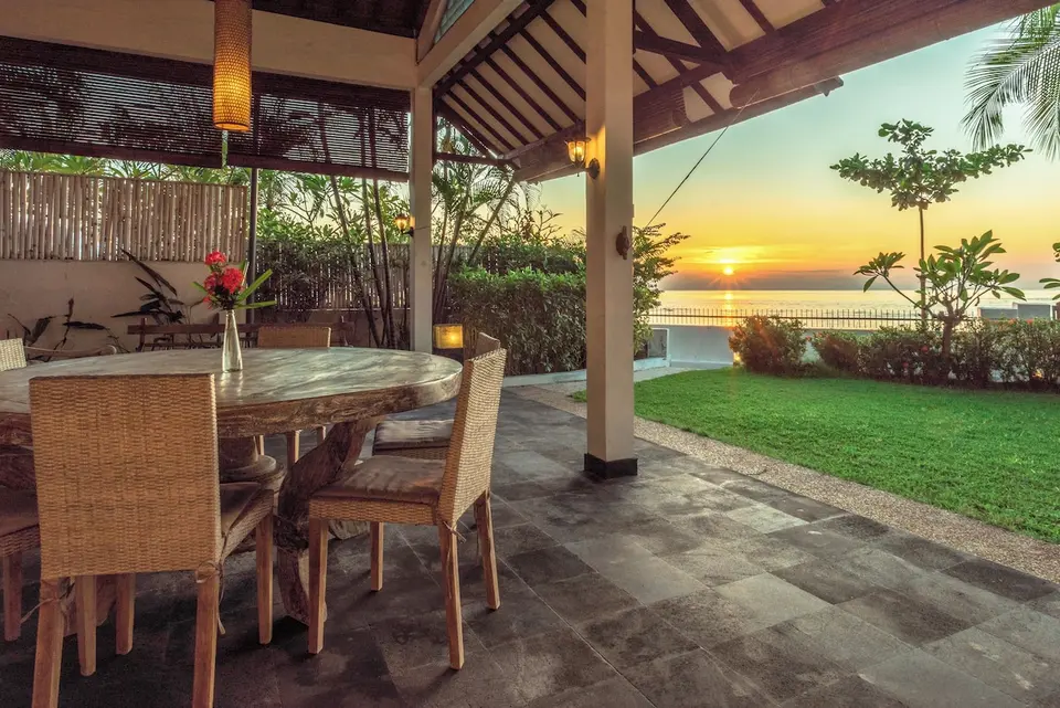 Overdækket spiseplads med rundt bord og solnedgang over havet på Mayo Resort