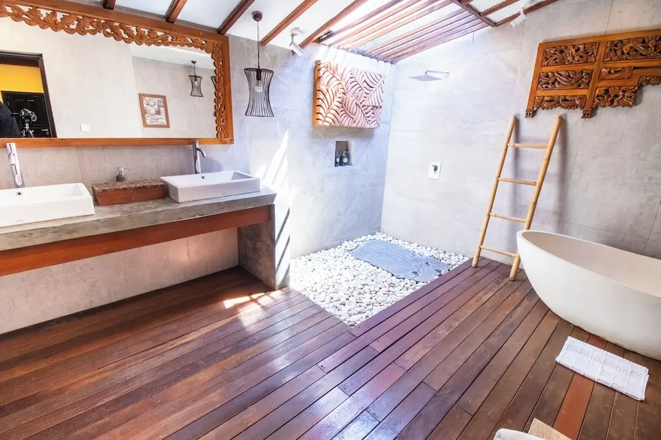Badeværelse med to håndvaske, bruser og badekar ved trægulv på Natya Hotel Tanah Lot