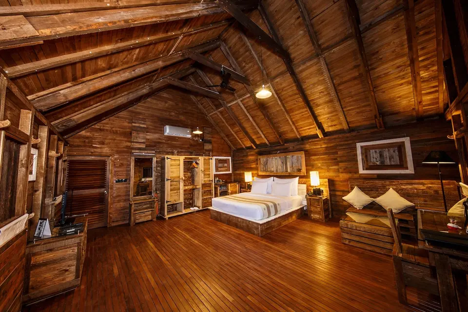Træchalet på Aliya Resort med dobbeltseng, siddeplads og højt skrånende træloft.