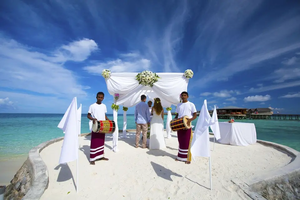 Ceremoni ved vandet med blomsterbue og trommeslagere på Centara Ras Fushi