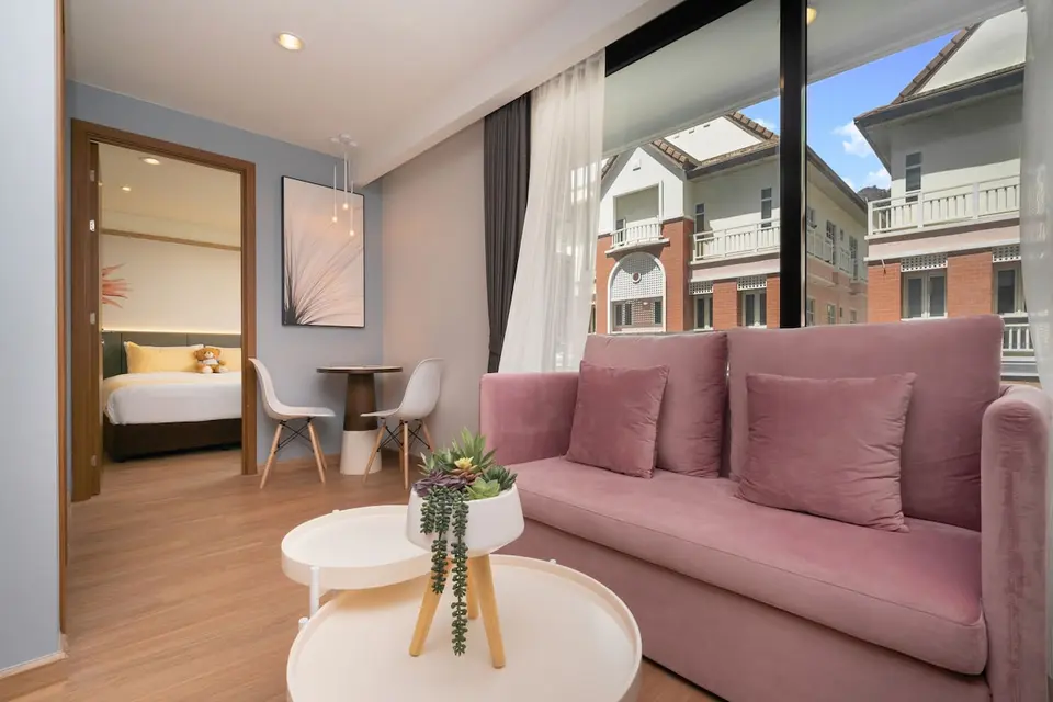 Opholdsrum på Wekata med rosa sofa, lille spisebord og dør ind til soveværelset.