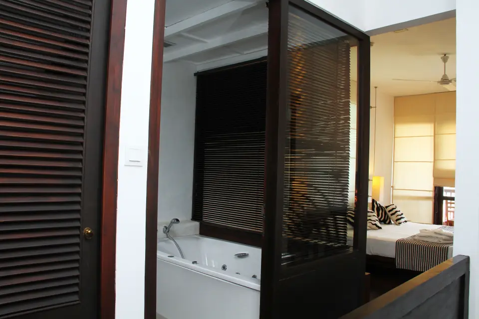Badeværelse med badekar og persienner ind mod soveværelset på Goldi Sands Hotel