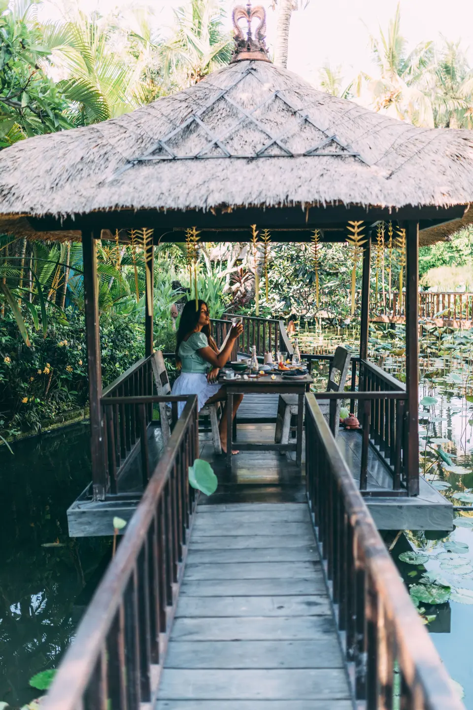 Træbro til en lille spisepavillon over dammen på Hotel Tugu Bali