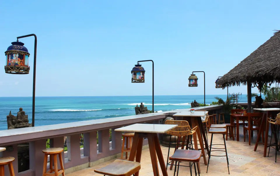 Restaurantterrasse på Hotel Tugu Bali med høje borde, dekorative lanterner og havudsigt.