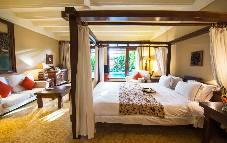 Værelse med himmelseng, sofa og træmøbler på Hotel Tugu Bali