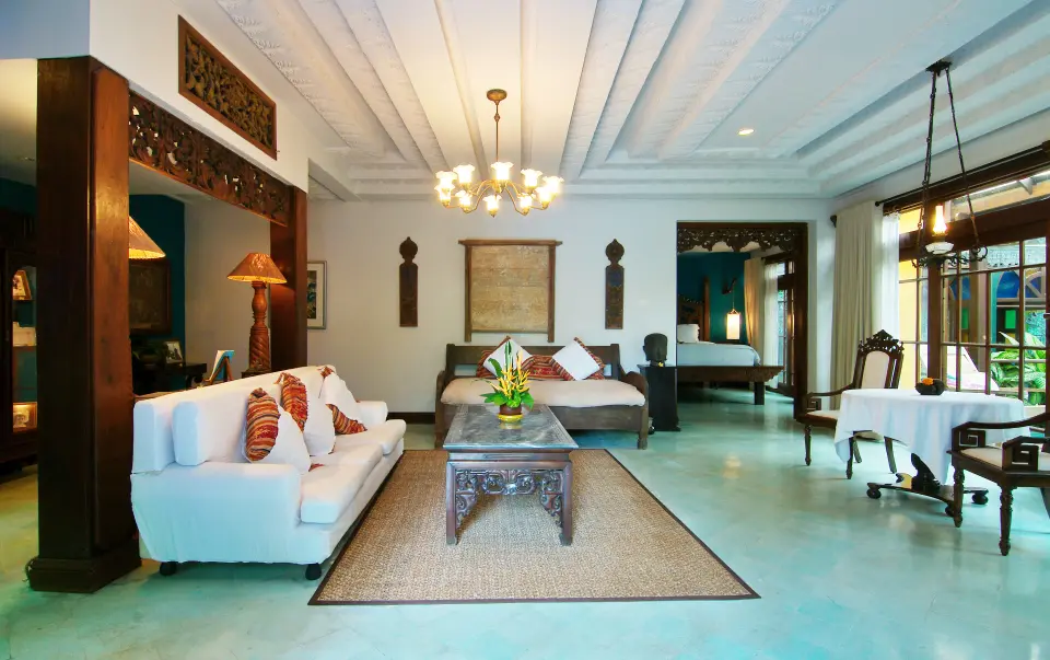 Stue på Hotel Tugu Bali med hvid sofa, udskåret træbord og lysekrone.