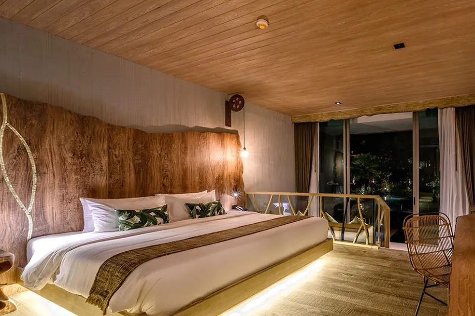 Soveværelse med dobbeltseng og træbeklædt væg på Kalima Resort & Villas Khao Lak