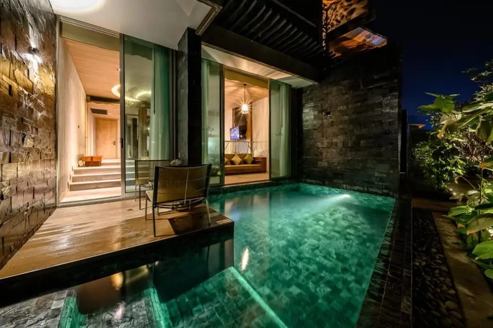 Oplyst pool ved en terrasse med åbne skydedøre på Kalima Khao Lak om aftenen