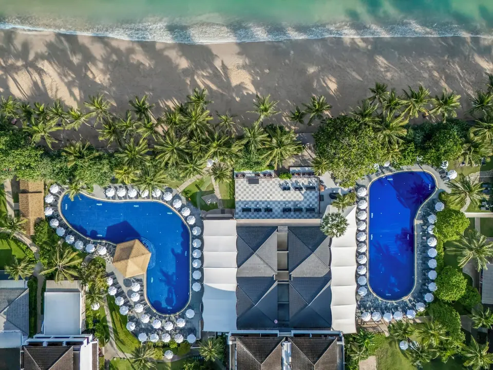 Sunprime Kamala Beach set oppefra med to pools, palmer og stranden.