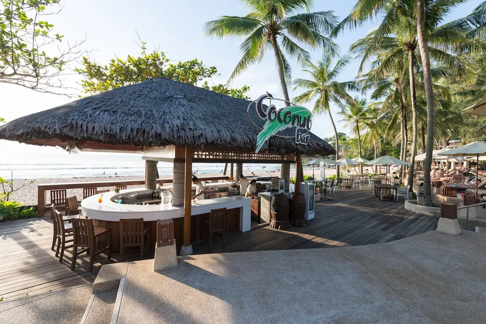 Strandbar med stråtag, bardisk og terrasse mellem palmer på Katathani Phuket Beach Resort.