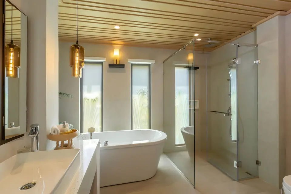 Badeværelse på Khaolak Merlin Resort med fritstående badekar, glasbruser og håndvask under et stort spejl